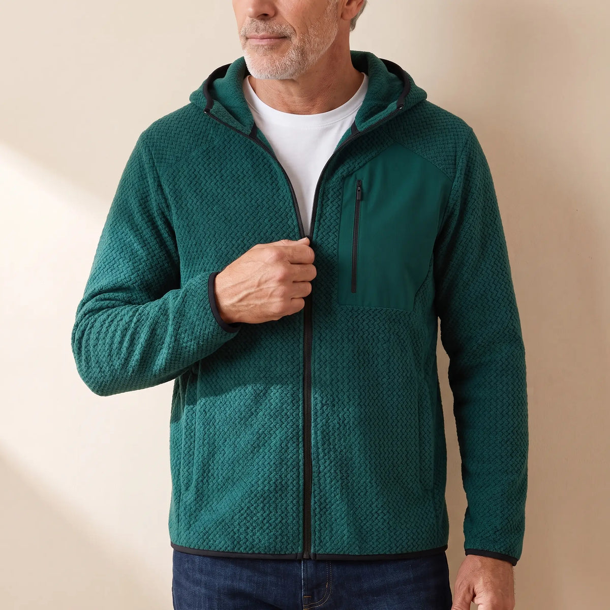 Man zipping up a green chevron knit hooded jacket