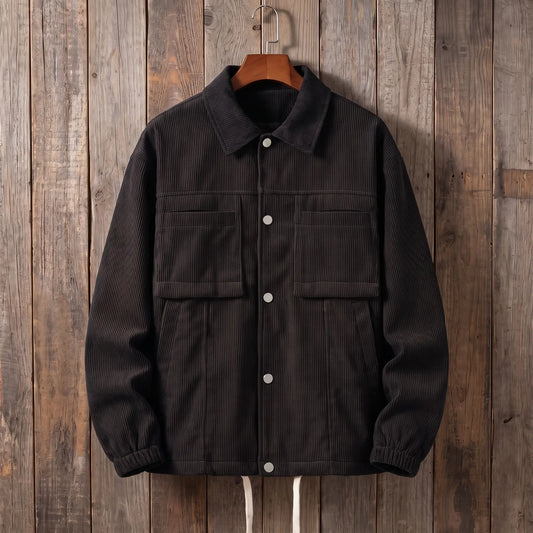 Men's black corduroy work jacket with snap front and flap chest pockets on a wooden hanger