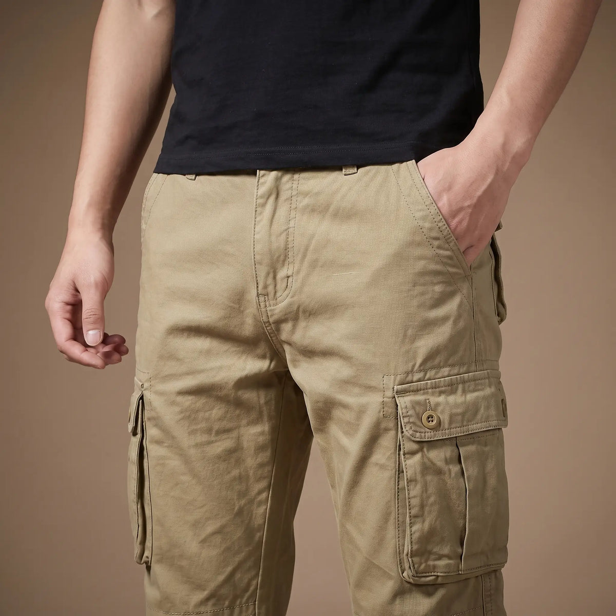 Man wearing the FLAP POCKET TROUSERS in khaki with a hand in the front pocket