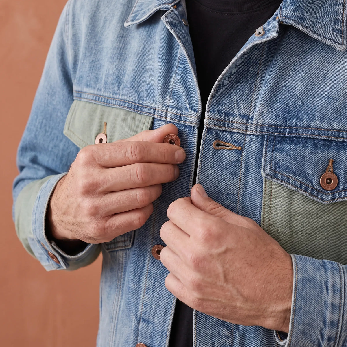 Older man fastening a copper shank button on the panelled denim jacket