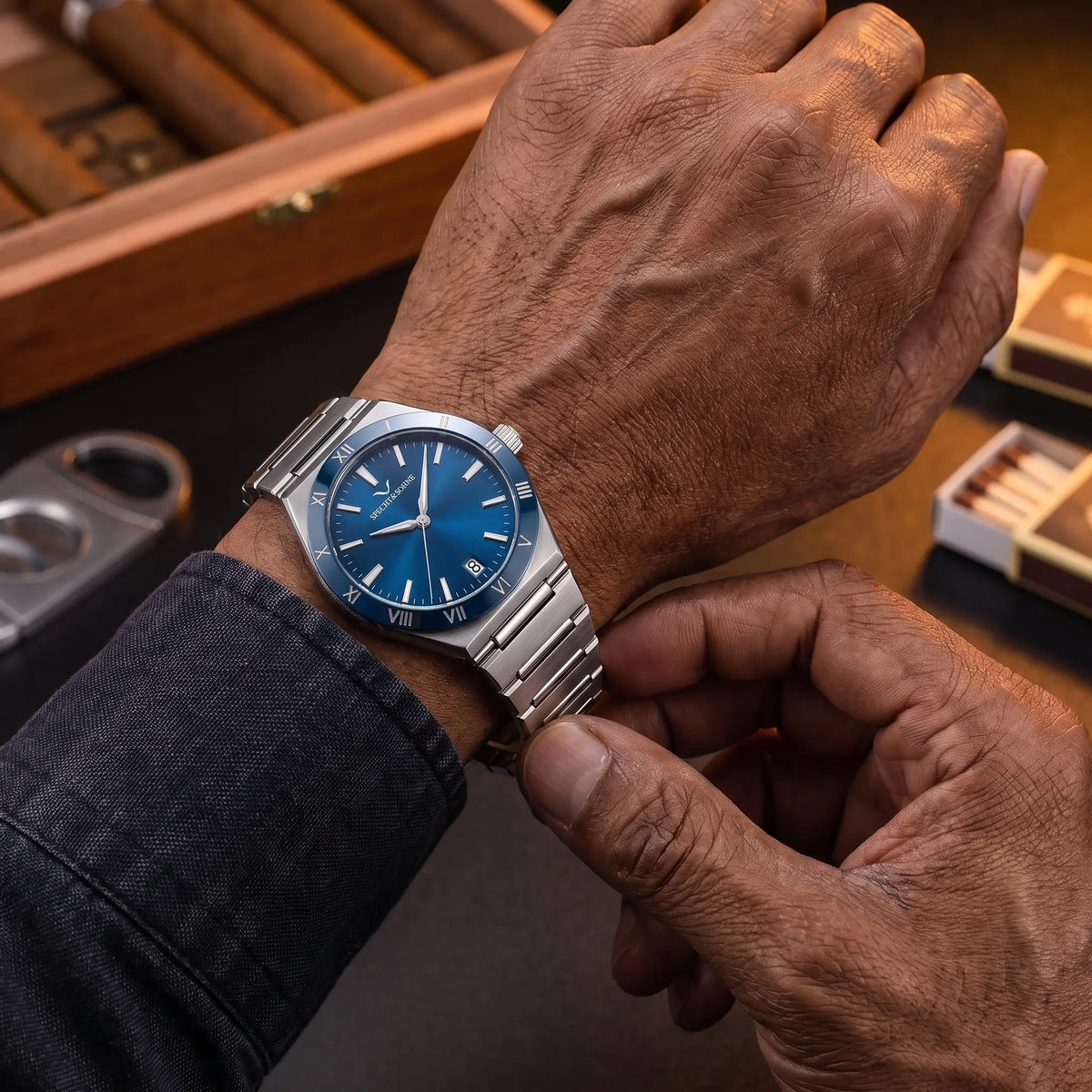 Man fastening the blue dial Roman bezel watch onto his wrist