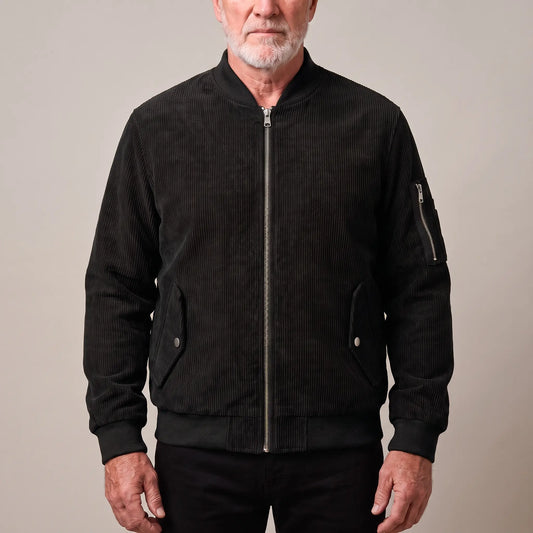Men's black corduroy bomber jacket with ribbed collar and snap-flap pockets, worn zipped