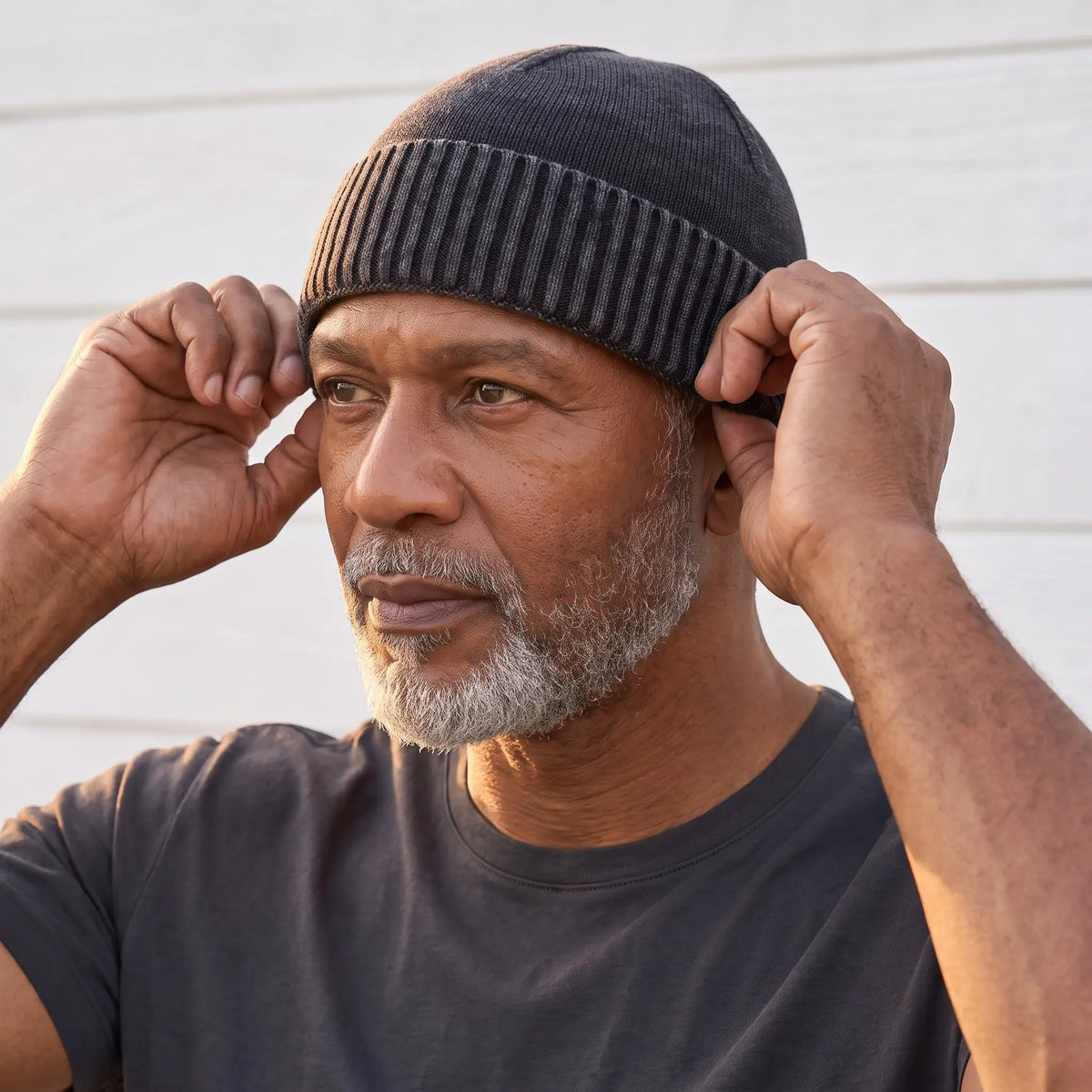 Man settling the black washed knit beanie onto his head