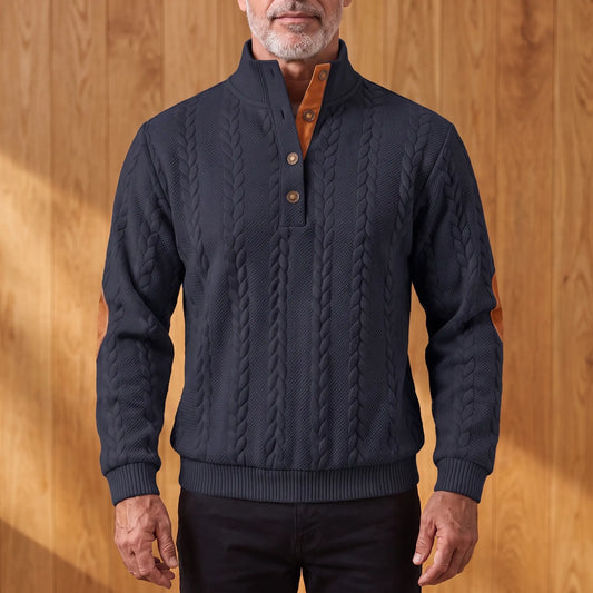 Men's navy blue cable knit henley sweater with stand collar, three-button placket and tan elbow patches, worn