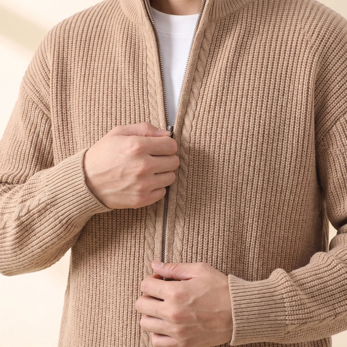 Man zipping up the khaki Cold Weather Cardigan knit jacket over a white tee