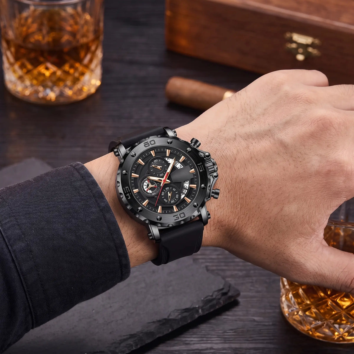 Man wearing the black Notched Bezel Watch with his forearm resting on a dark desk