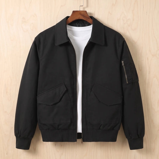 Sleeve Pocket Bomber in black, a short flight bomber jacket with a zip front, hip flap pockets and a zipped sleeve pocket on a wooden hanger