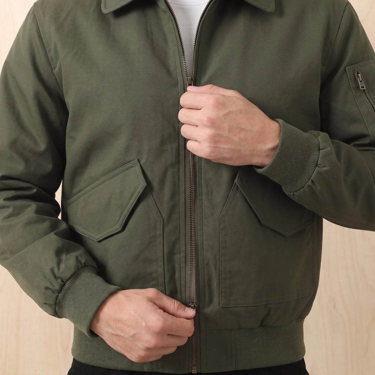 Man zipping up the green Sleeve Pocket Bomber over a white tee