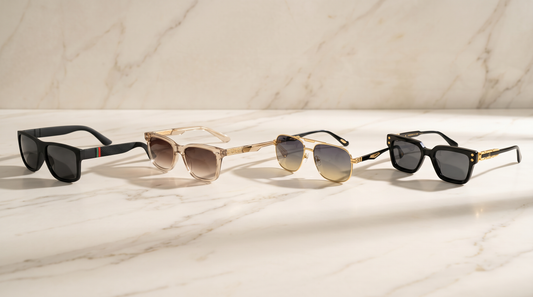 Four men's sunglasses frames laid in a row on cream marble for different face shapes