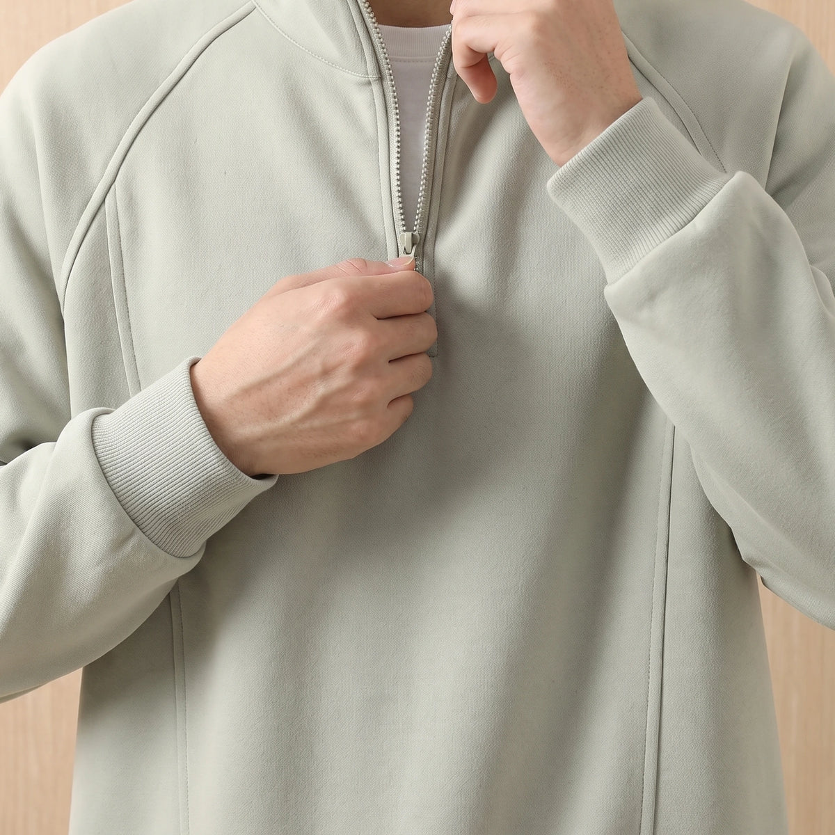 Man pulling up the short zip on the green oversized sweatshirt, close chest view