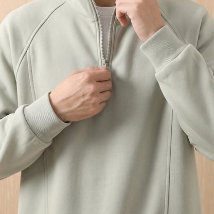 Man pulling up the short zip on the green oversized sweatshirt, close chest view