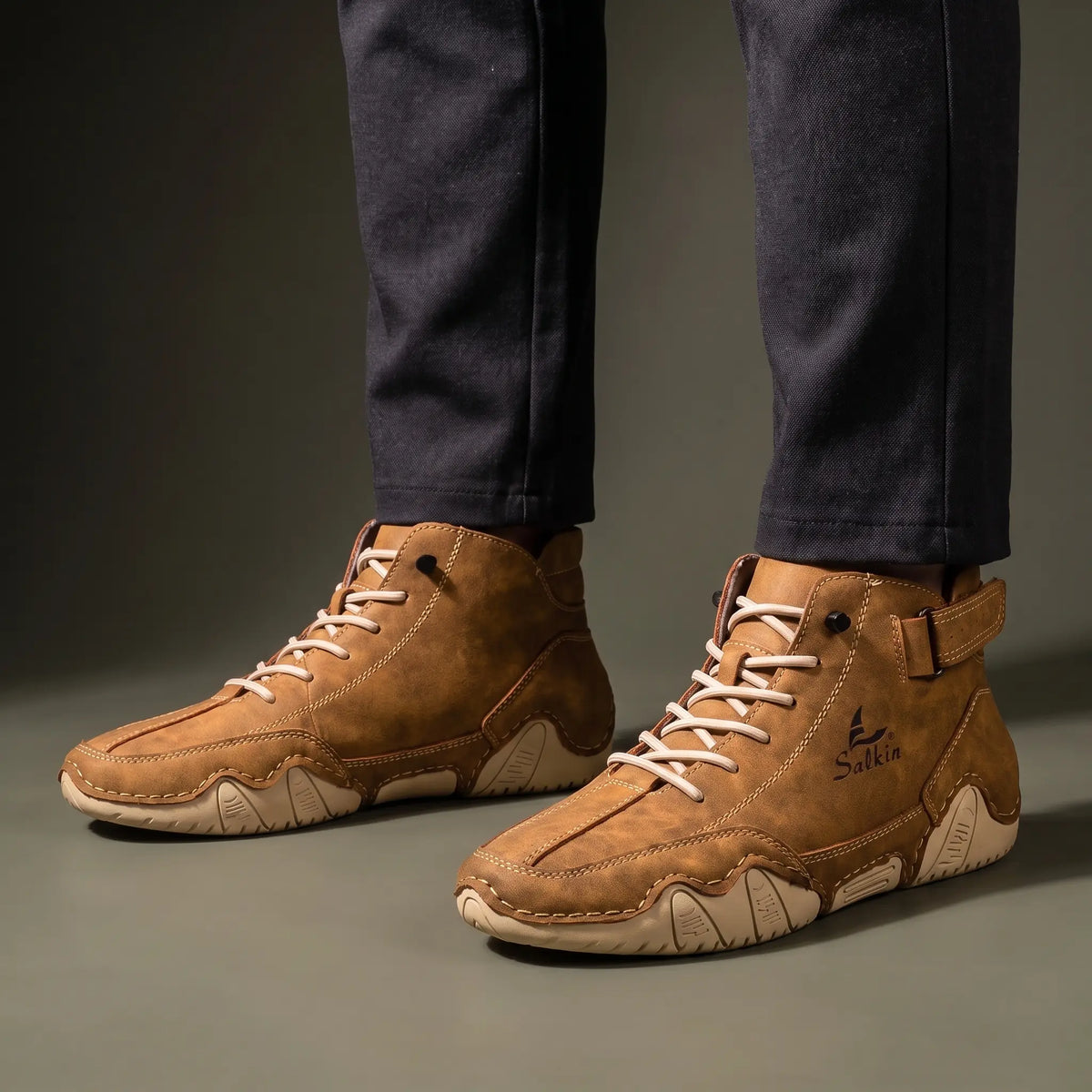 Man standing in a pair of tan brown padded collar ankle boots with charcoal trousers
