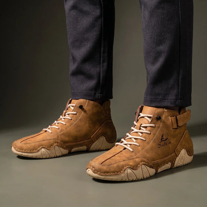 Man standing in a pair of tan brown padded collar ankle boots with charcoal trousers