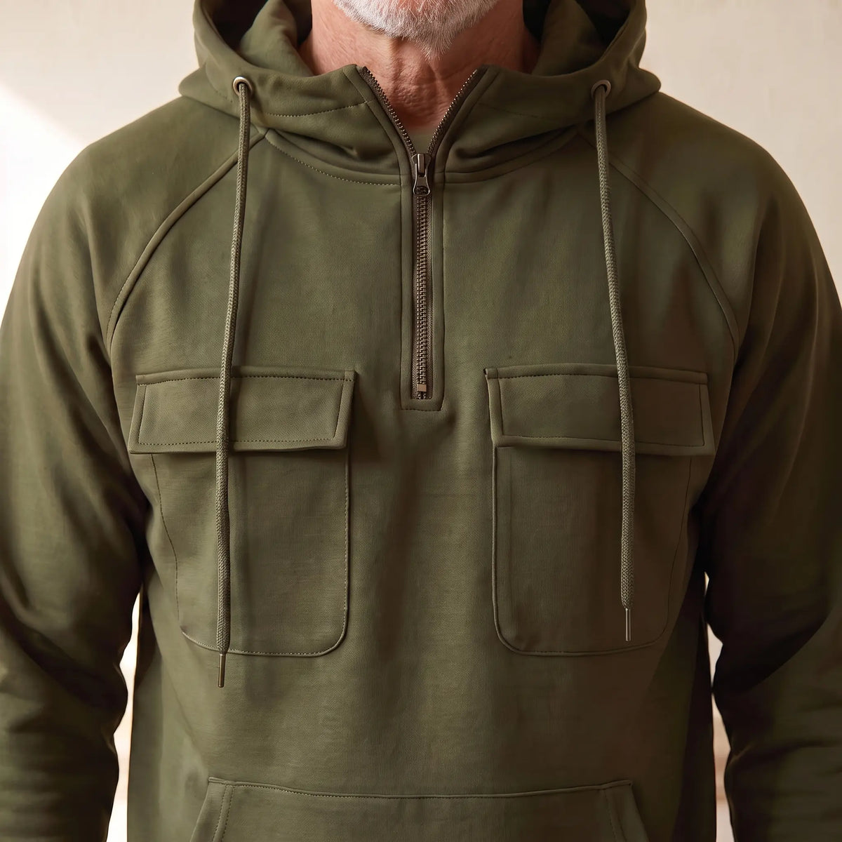 Close-up of the half zip placket and twin chest flap pockets on the olive green hooded anorak