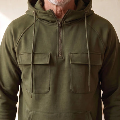 Close-up of the half zip placket and twin chest flap pockets on the olive green hooded anorak