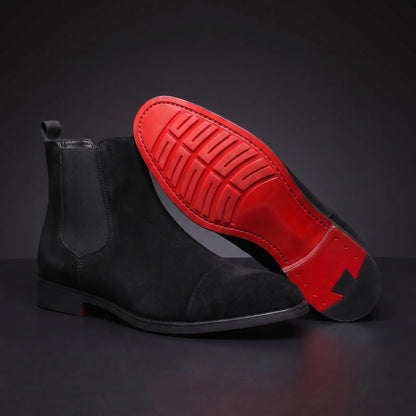 RED SOLE BOOTS matte black Chelsea boot propped toe-up showing the detailed red lugged sole, dark charcoal scene