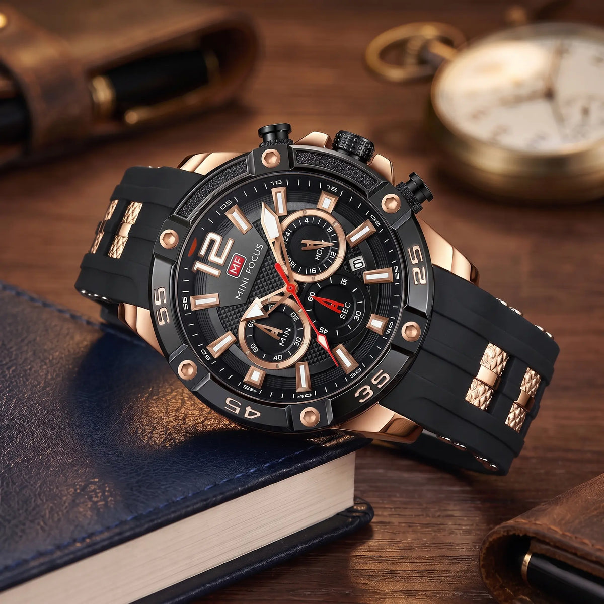 Men's rose gold and black sport chronograph watch with screw-set bezel and black silicone strap, resting on leather-bound books