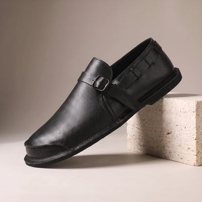 CLASSIC SLIP-ON LOAFERS black leather slip-on loafer with vamp strap on a travertine studio block