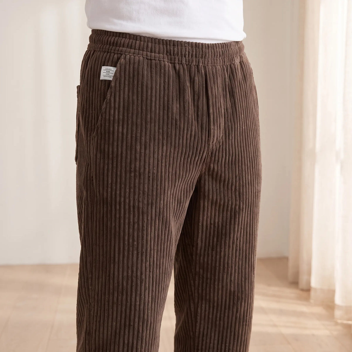 Close-up of the elastic waistband and woven label on the brown corduroy trousers