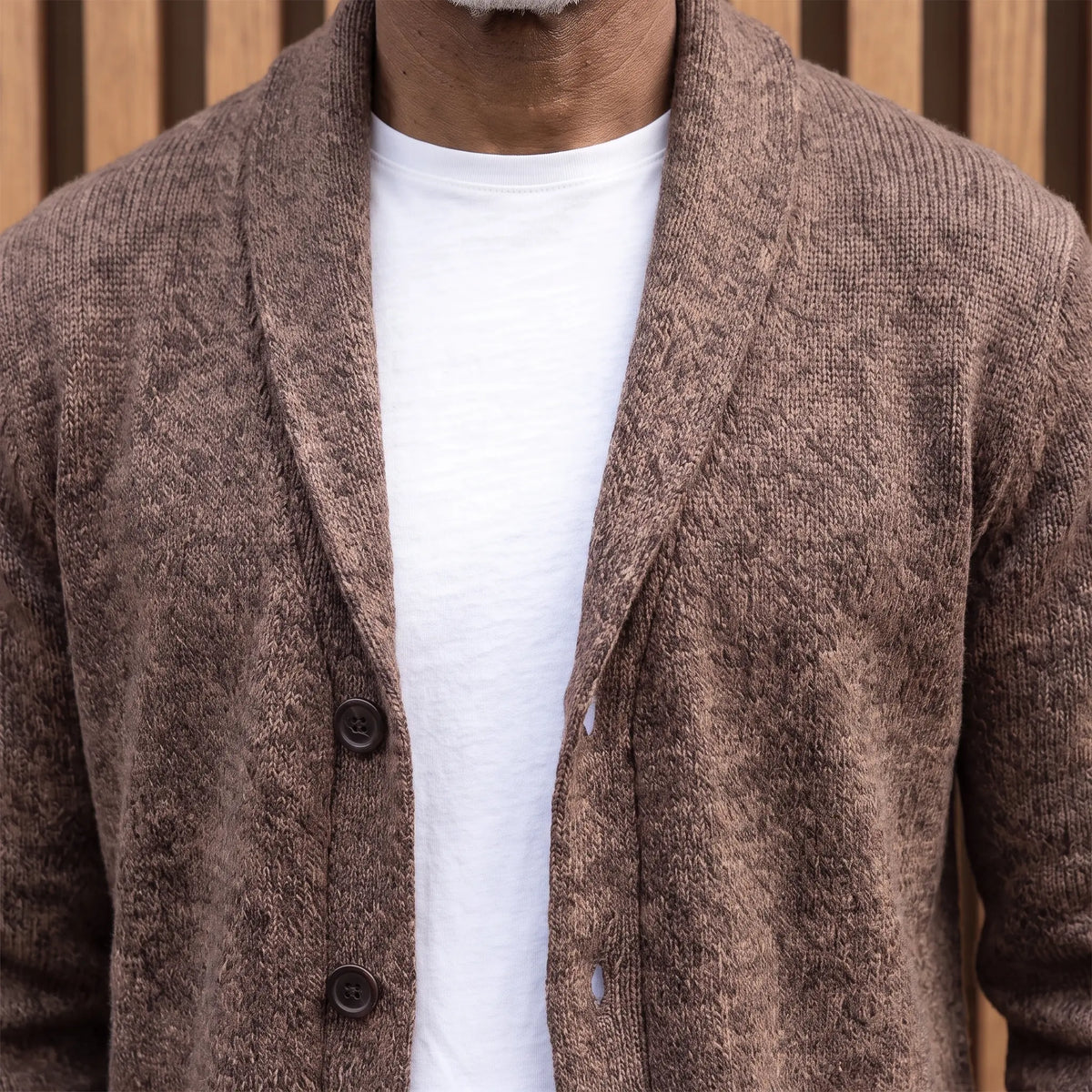 Close-up of the rolled shawl collar and button front on the brown knit cardigan