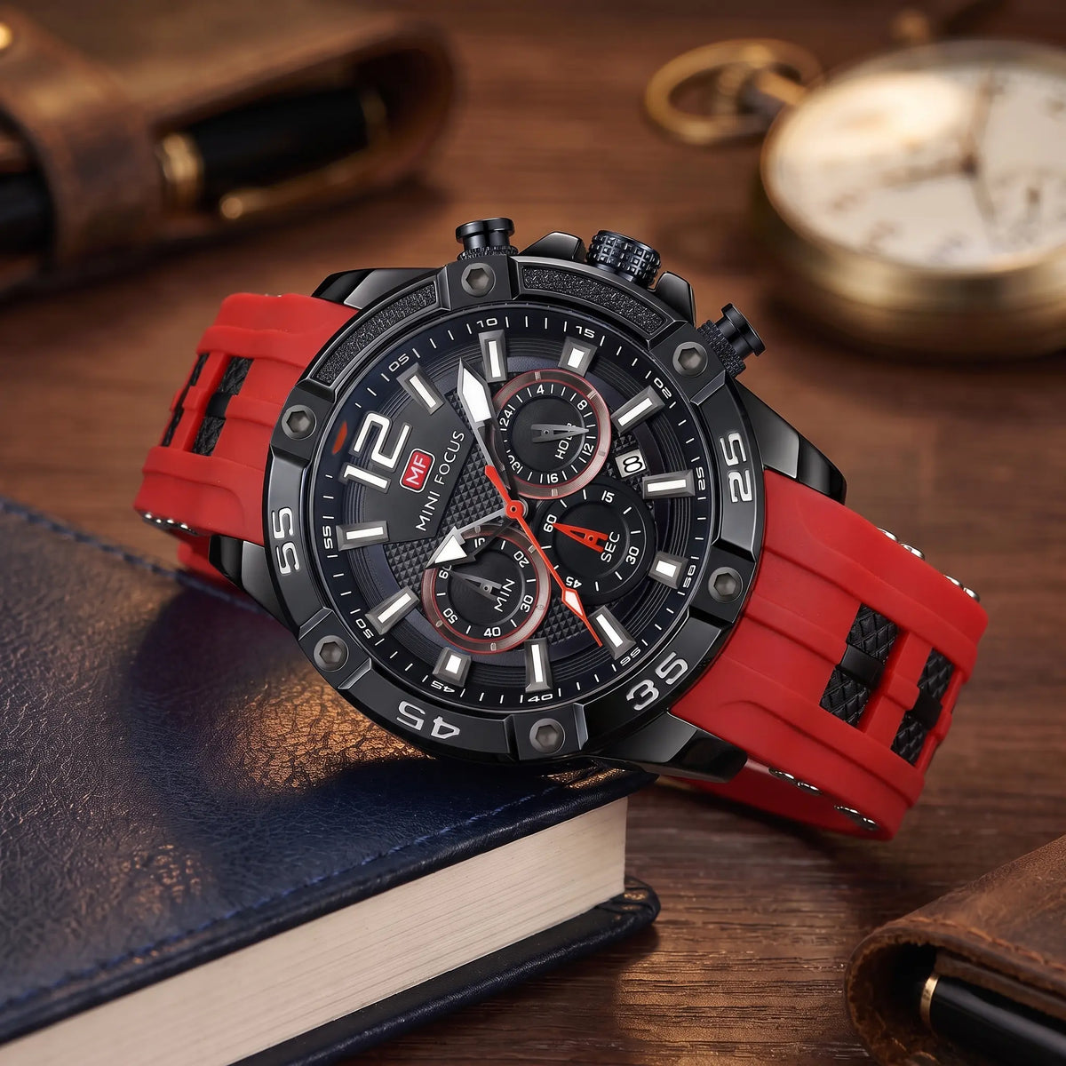 Men's red sport chronograph watch with screw-set black bezel and red silicone strap, resting on leather-bound books