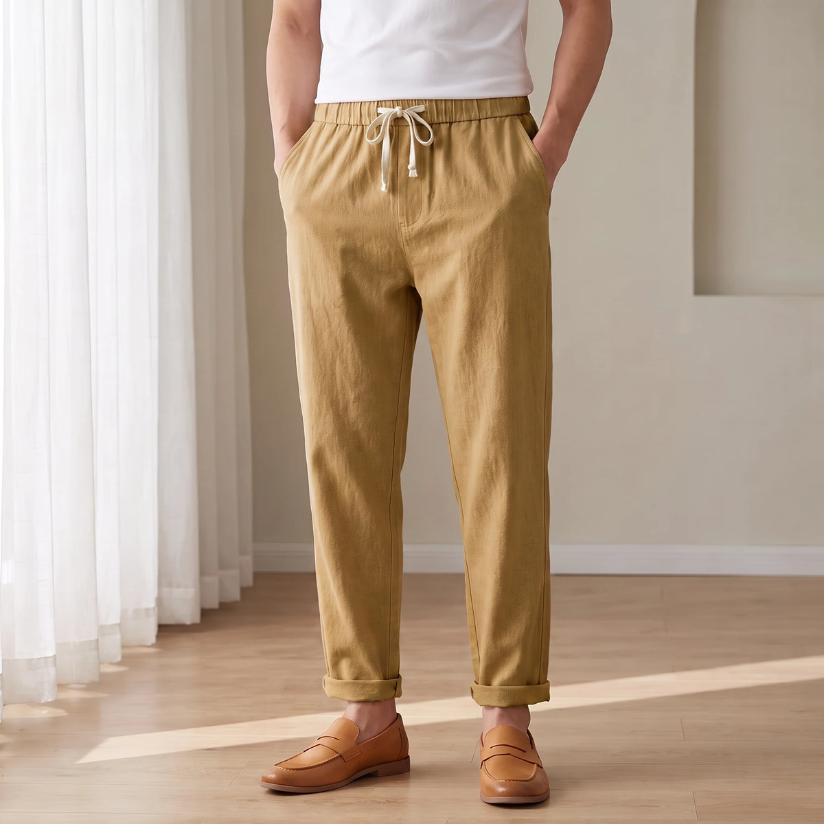 Drawstring cotton linen trousers in tan, worn in a bright airy room
