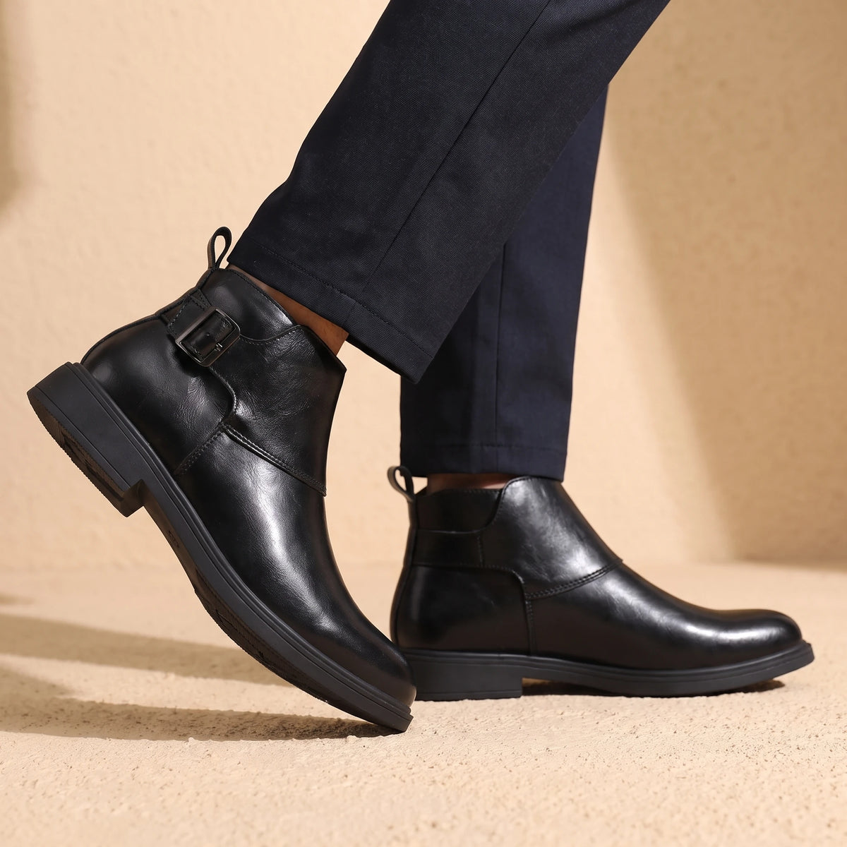 Man wearing black leather Chelsea boots mid-stride
