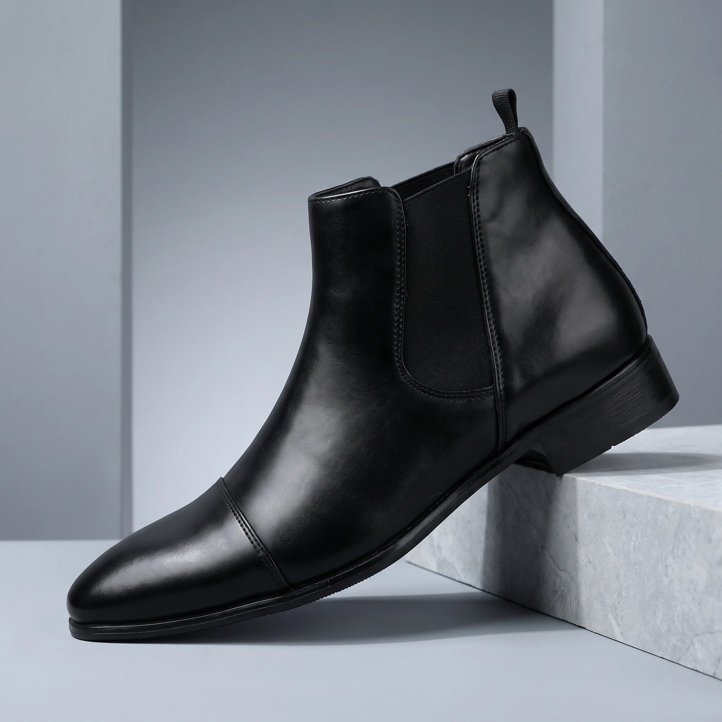 SMOOTH GENTLEMAN BOOTS black Chelsea boot on a grey stone plinth in a cool grey studio