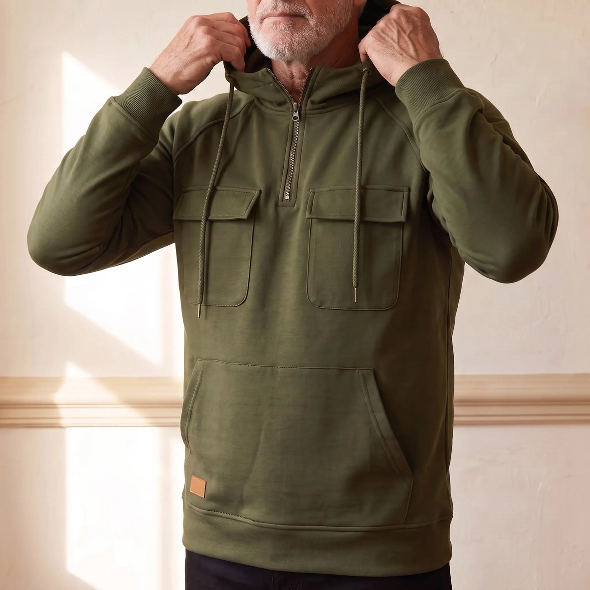 Man pulling the hood up on the olive green flap pocket hoodie