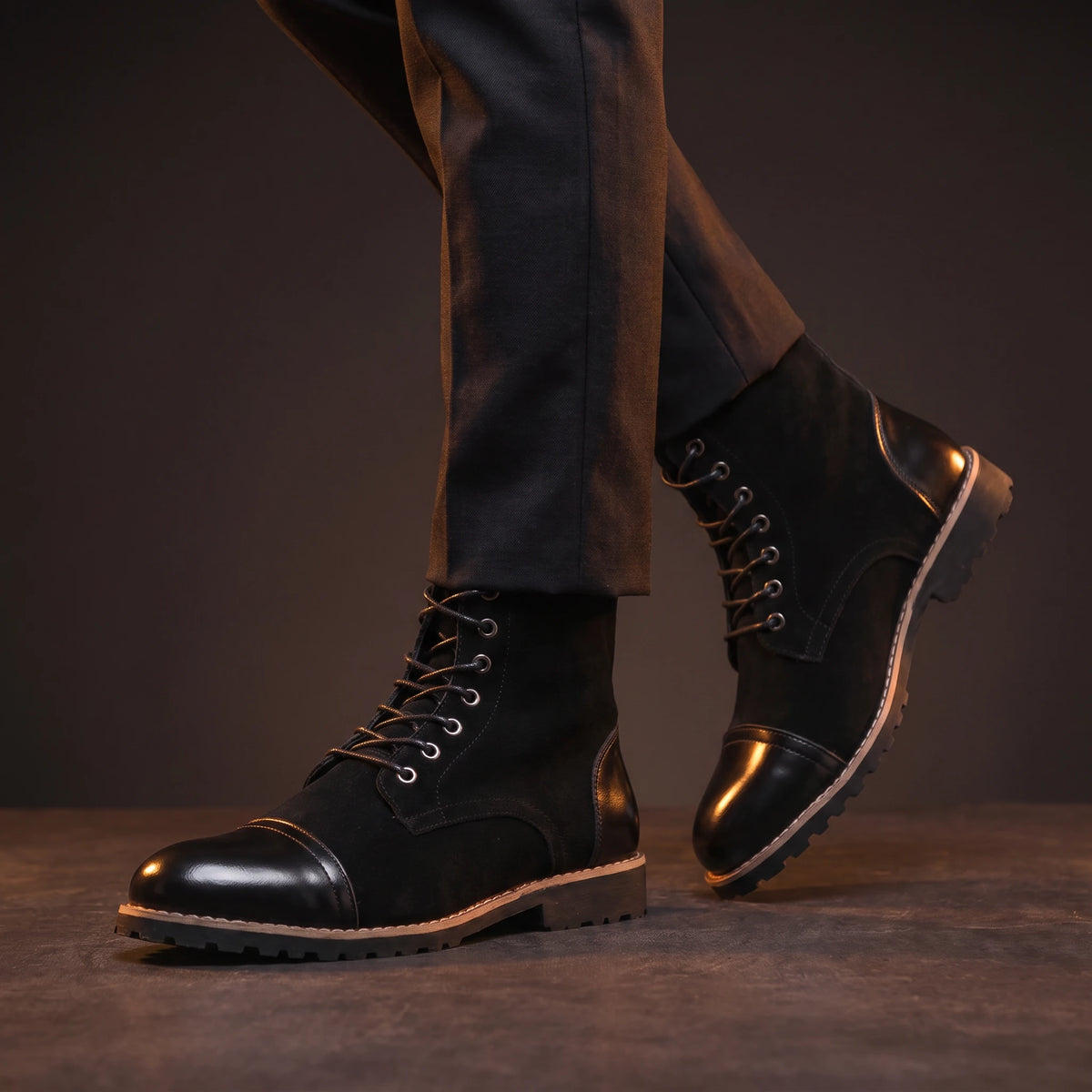 Man wearing black glossy leather ankle boots mid-stride