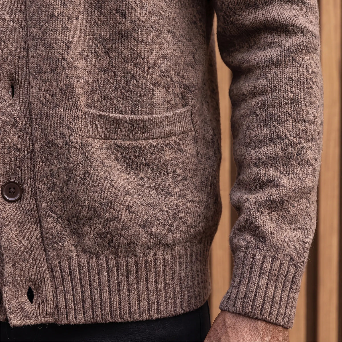 Close-up of the welt hand pocket and ribbed hem on the brown knit cardigan
