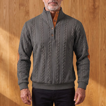 Men's charcoal grey cable knit henley sweater with stand collar, three-button placket and tan elbow patches, worn