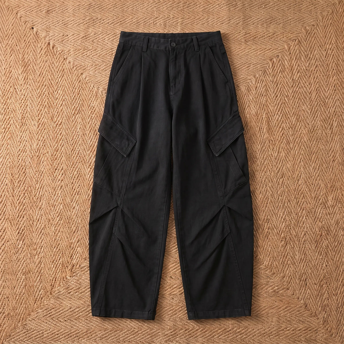 Baggy cargo trousers in washed black cotton laid flat on a jute rug