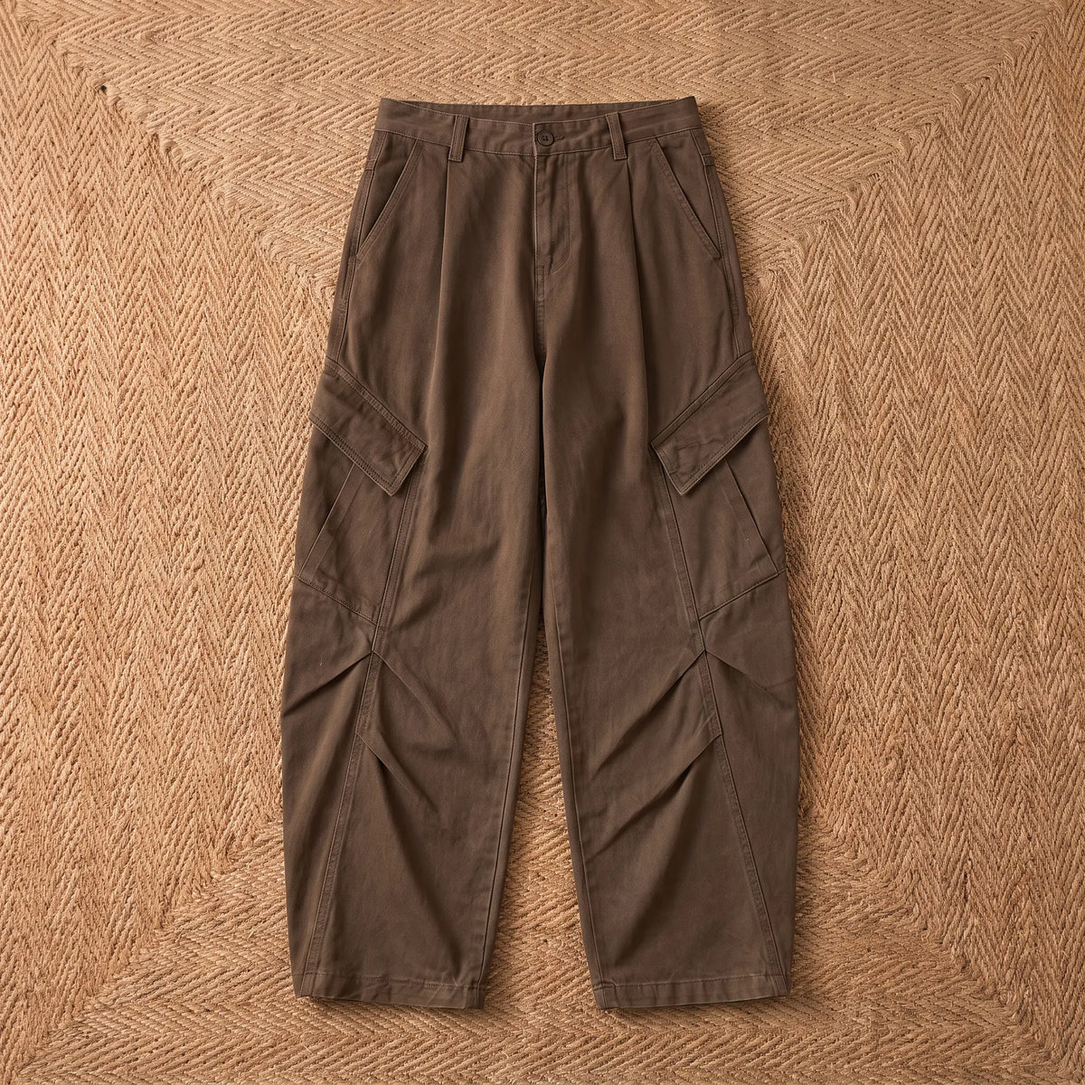 Baggy cargo trousers in washed brown cotton laid flat on a jute rug