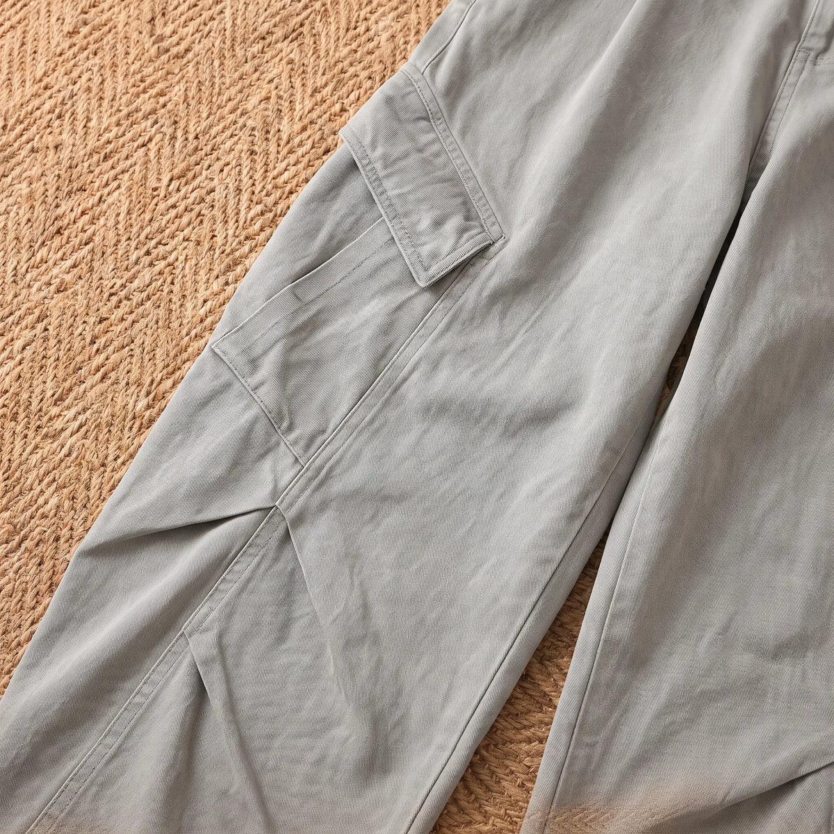 Close-up of the grey baggy cargo trousers flap cargo pocket and knee seams