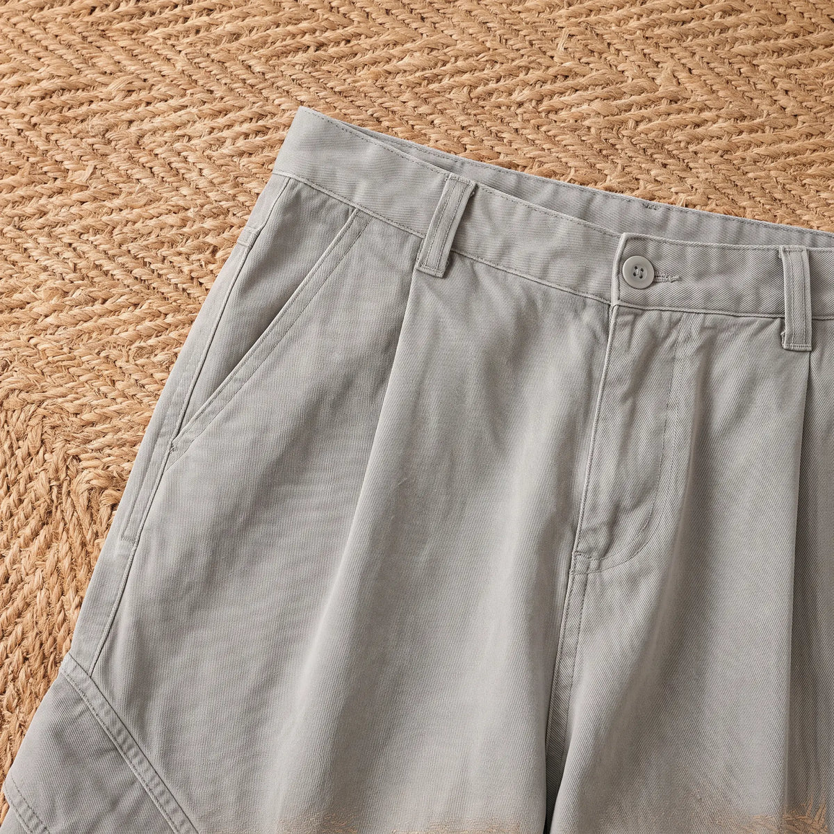 Close-up of the grey baggy cargo trousers waistband, button and front pocket