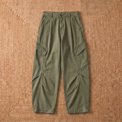 Baggy cargo trousers in washed green cotton laid flat on a jute rug