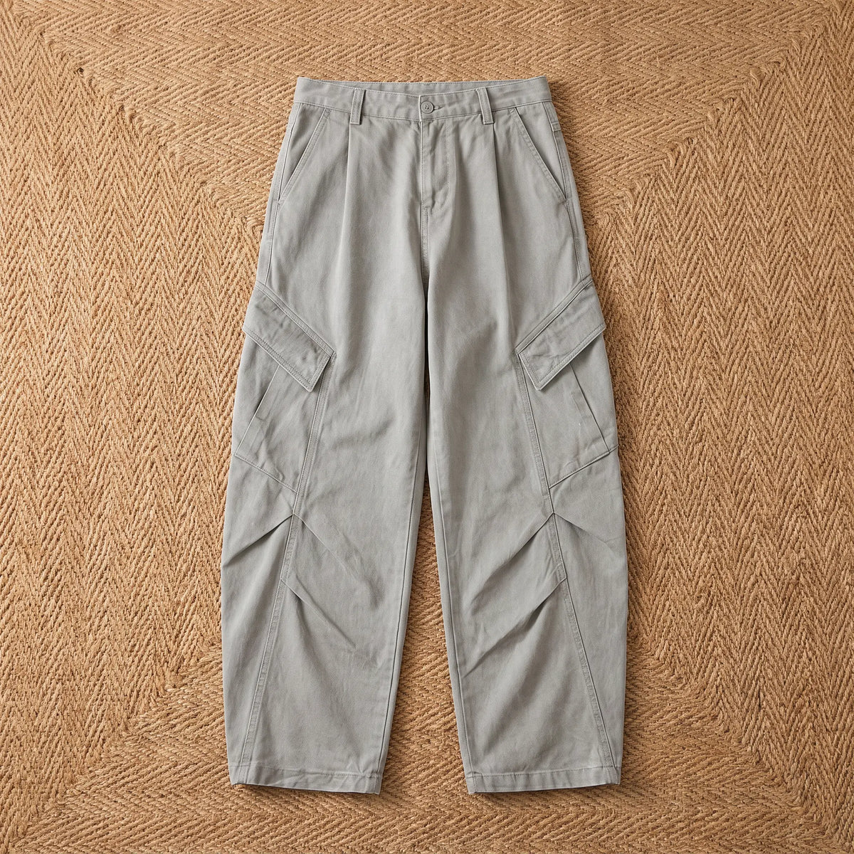Baggy cargo trousers in washed grey cotton laid flat on a jute rug