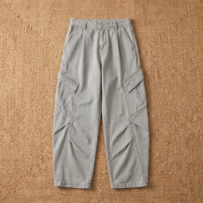 Baggy cargo trousers in washed grey cotton laid flat on a jute rug