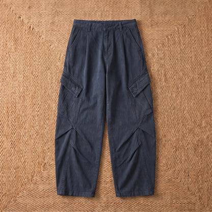 Baggy cargo trousers in washed navy blue cotton laid flat on a jute rug