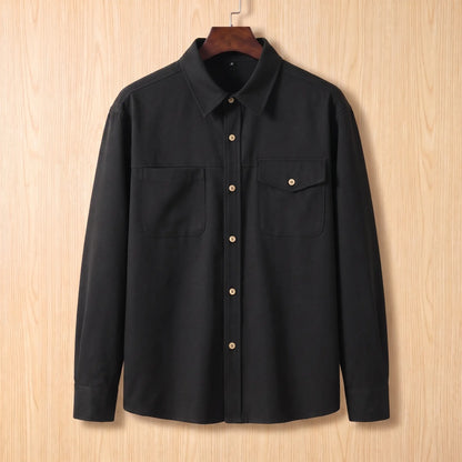 Boxy Cotton Overshirt in black, a loose fit utility overshirt with asymmetric chest pockets on a wooden hanger