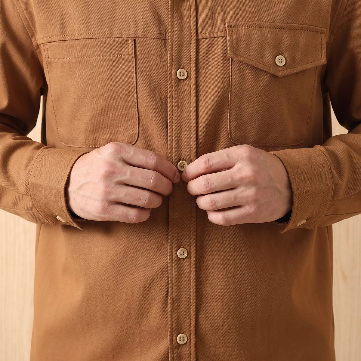 Man buttoning up the brown Boxy Cotton Overshirt