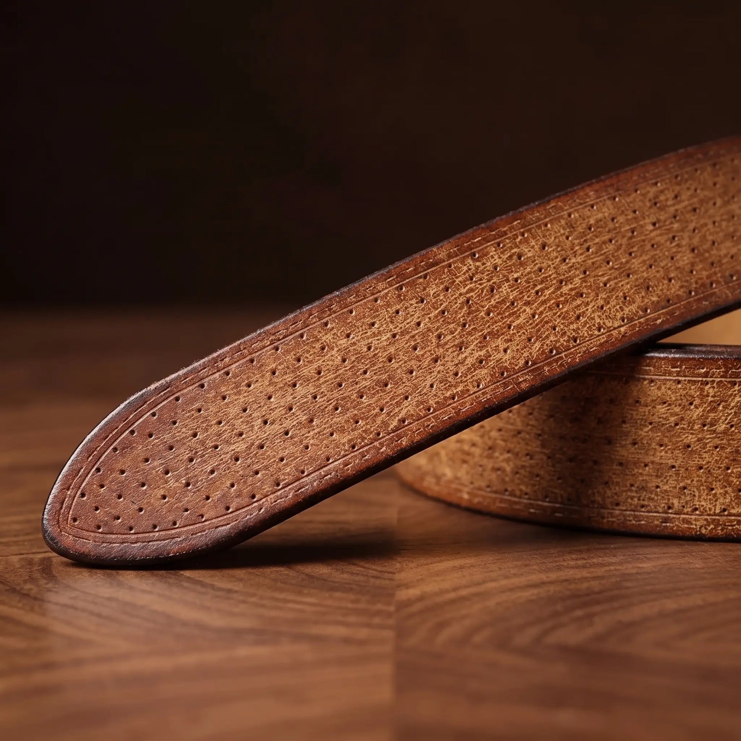 Close up of the dotted leather texture and rounded tip on the tan brass ring belt