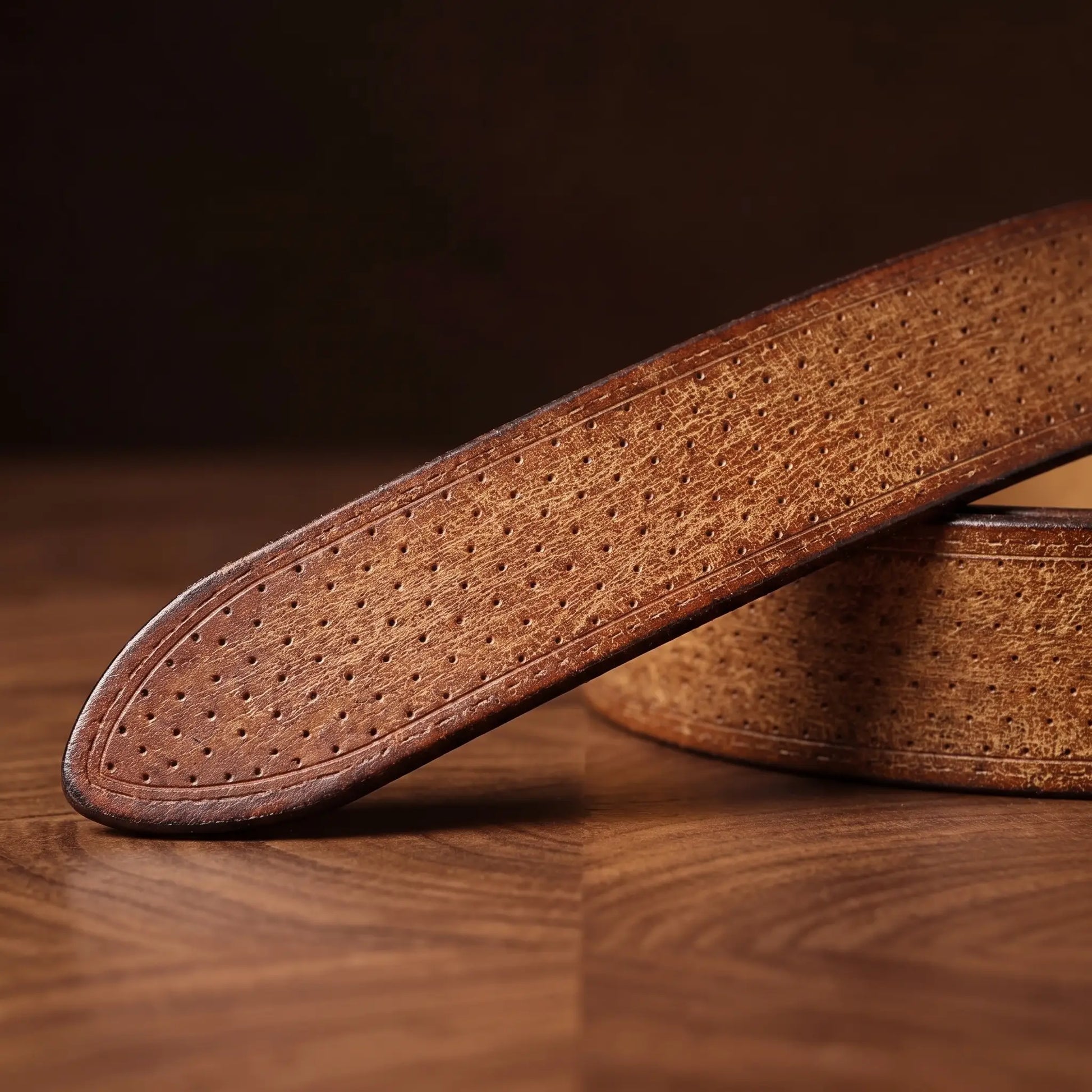 Close up of the dotted leather texture and rounded tip on the tan brass ring belt