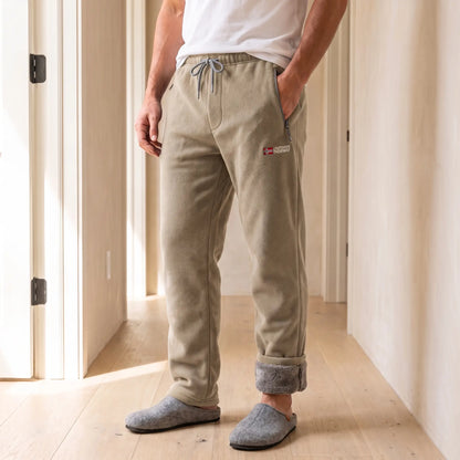 Men's khaki sherpa-lined fleece trousers with drawcord waist and rolled cuffs, worn with slippers in a bright hallway