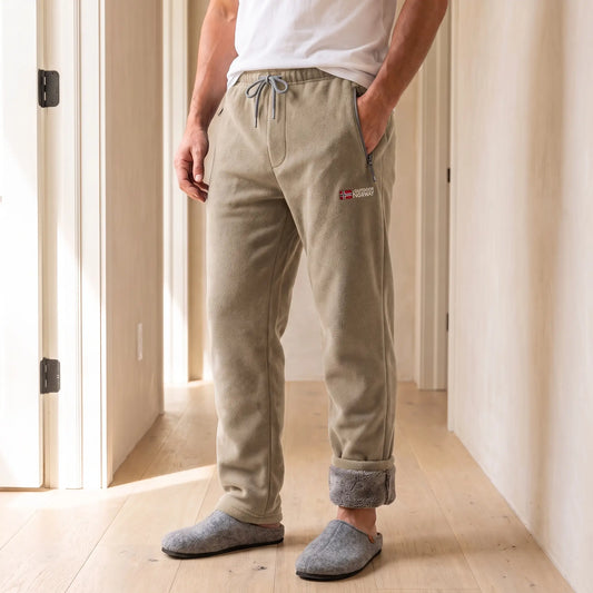 Men's khaki sherpa-lined fleece trousers with drawcord waist and rolled cuffs, worn with slippers in a bright hallway