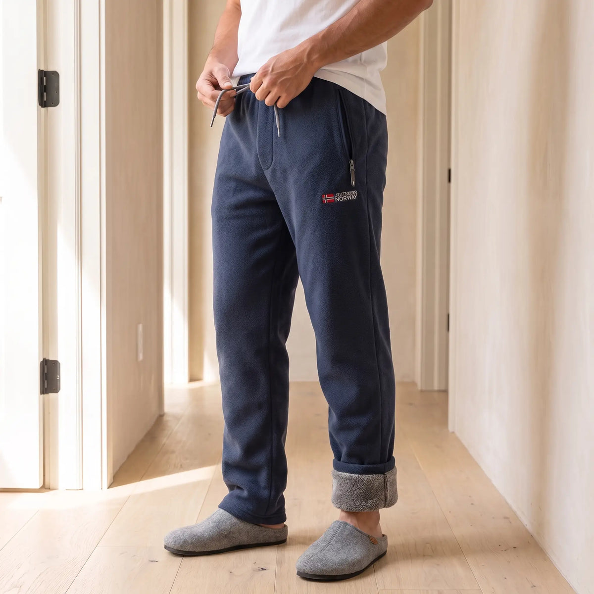 Man tying the drawcord of navy blue cabin fleece trousers