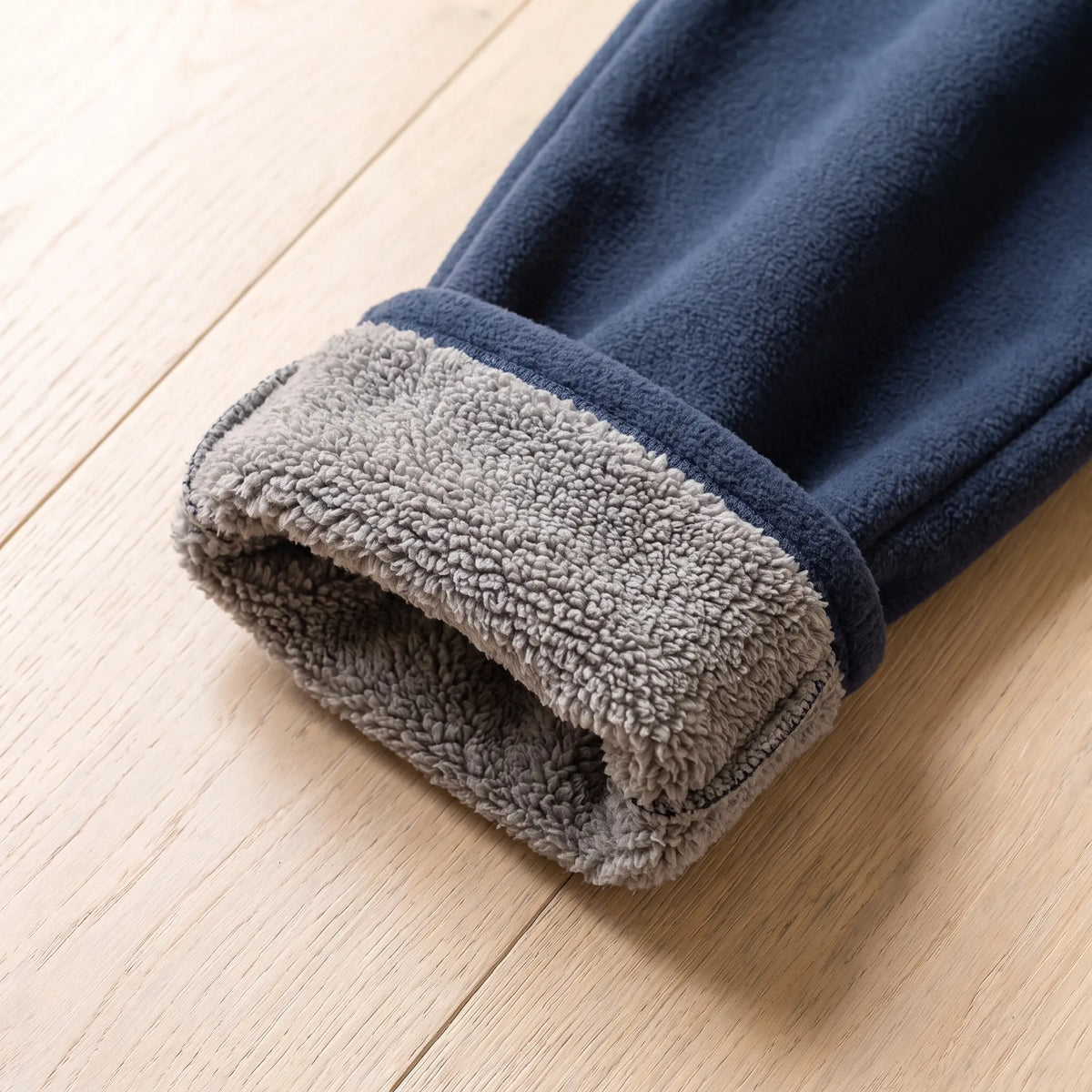 Rolled cuff of navy blue fleece trousers showing grey sherpa lining