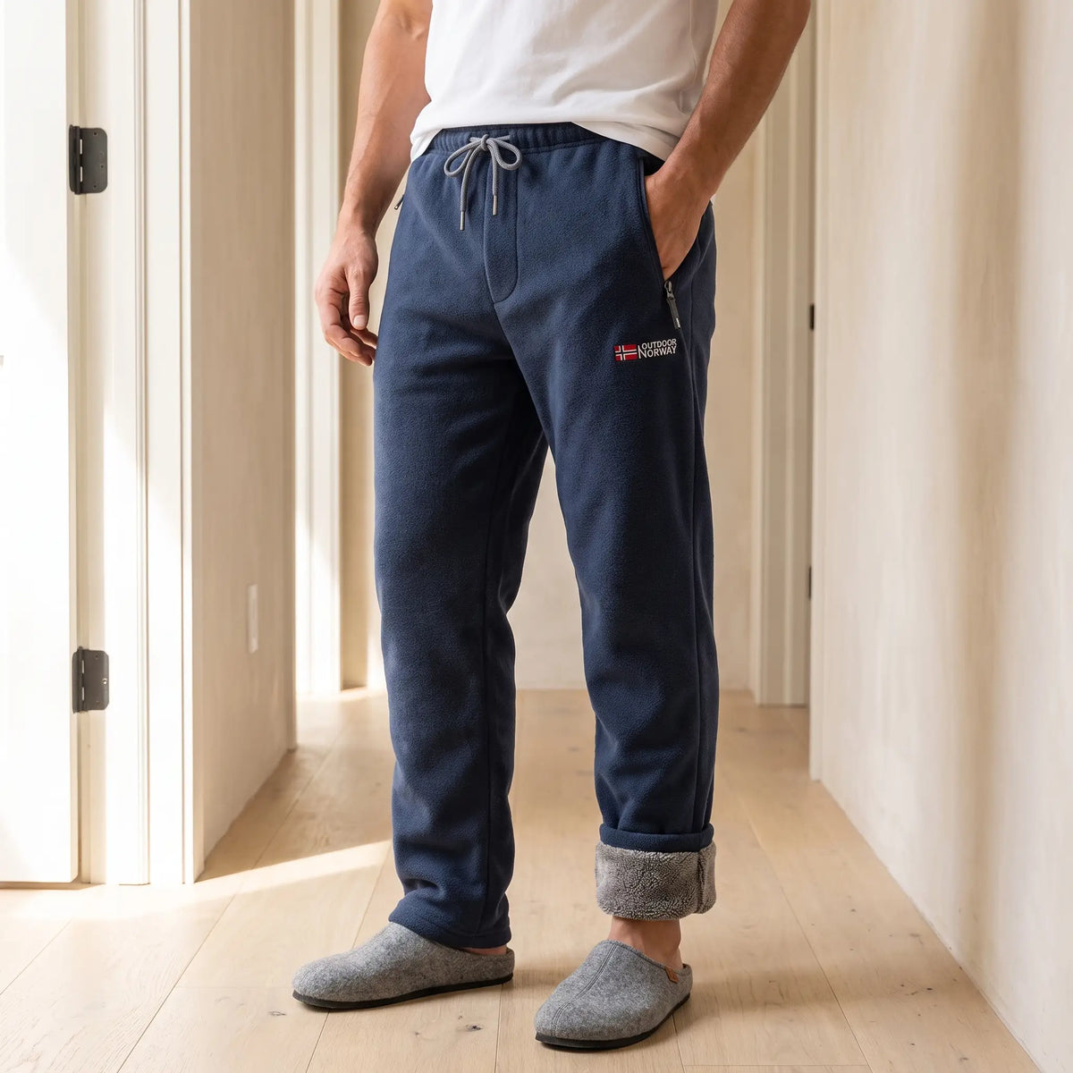 Men's navy blue sherpa-lined fleece trousers with drawcord waist and rolled cuffs, worn with slippers in a bright hallway
