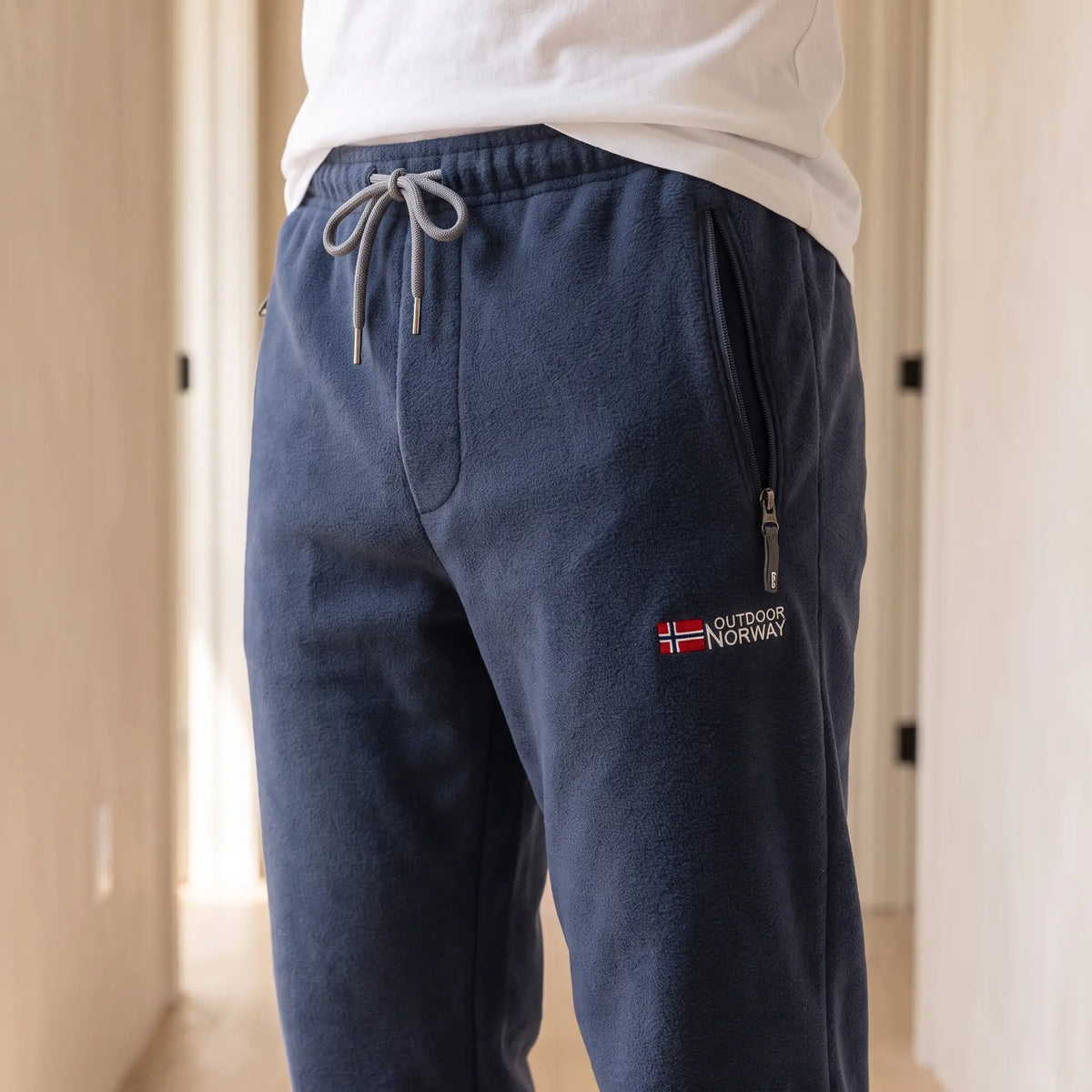 Close-up of navy blue fleece trousers drawcord waist and zip pocket